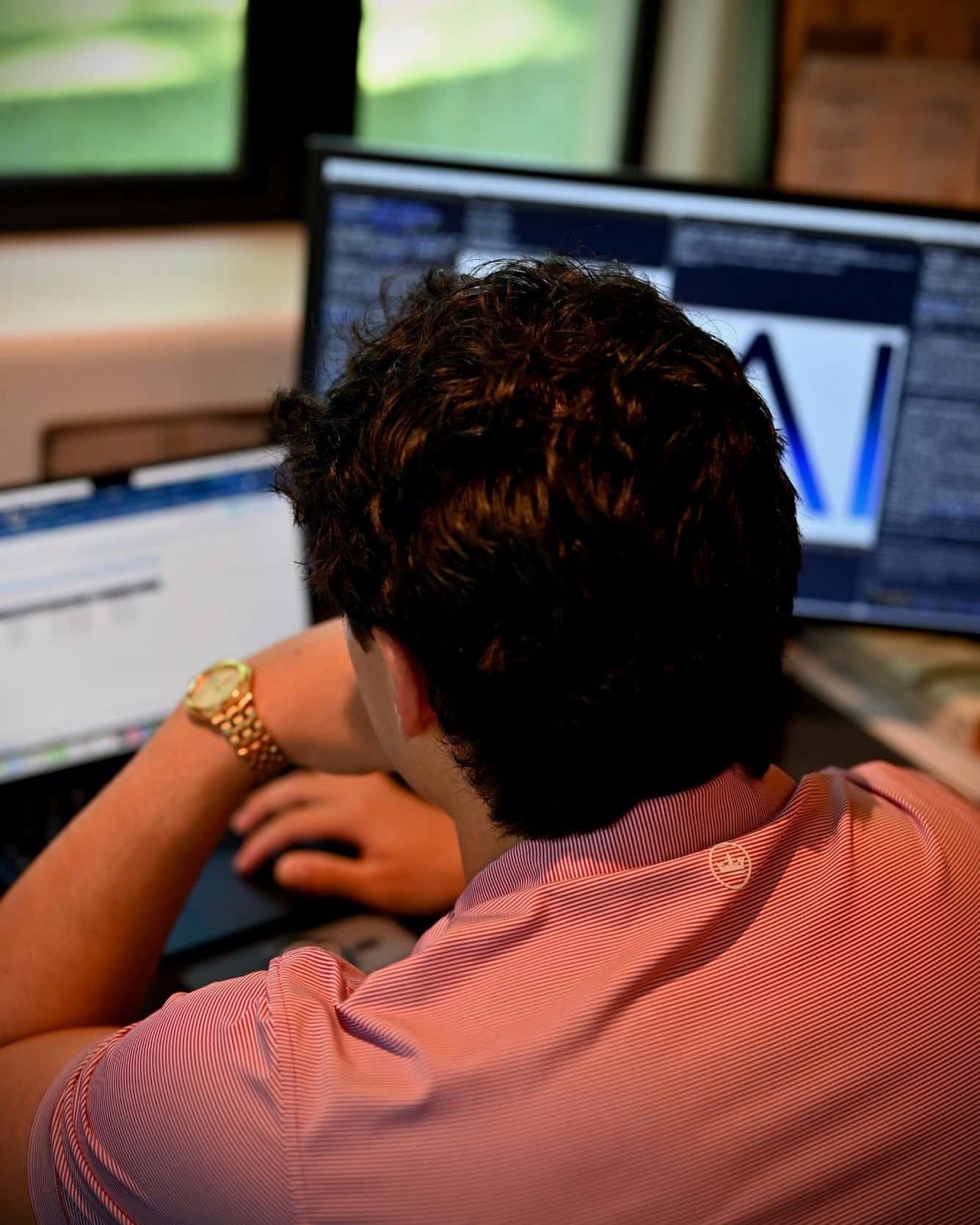 Roman Lubetzky working at his desk in the 6AI office, seen from behind, with code and the 6AI wordmark on the monitor